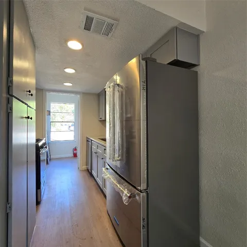 a kitchen with granite countertop a sink cabinets a stove and wooden floor