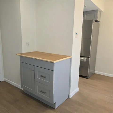 a view of an empty room with wooden floor and a fan