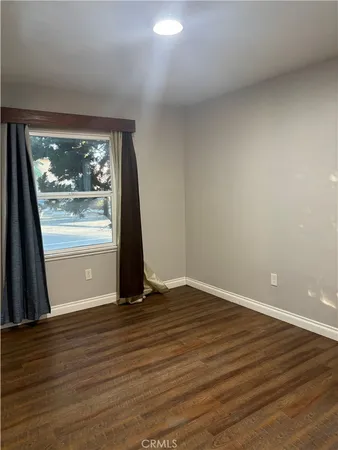 a view of an empty room with wooden floor and closet