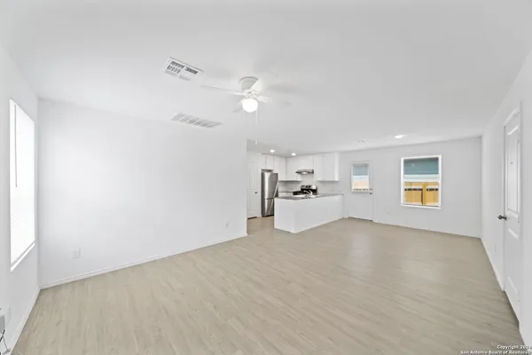 a view of empty room with wooden floor and kitchen view