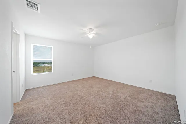 an empty room with a fan & a window