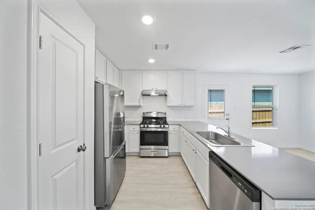 a large kitchen with stainless steel appliances granite countertop a lot of counter space and a sink