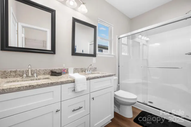 a bathroom with a granite countertop sink toilet mirror and shower