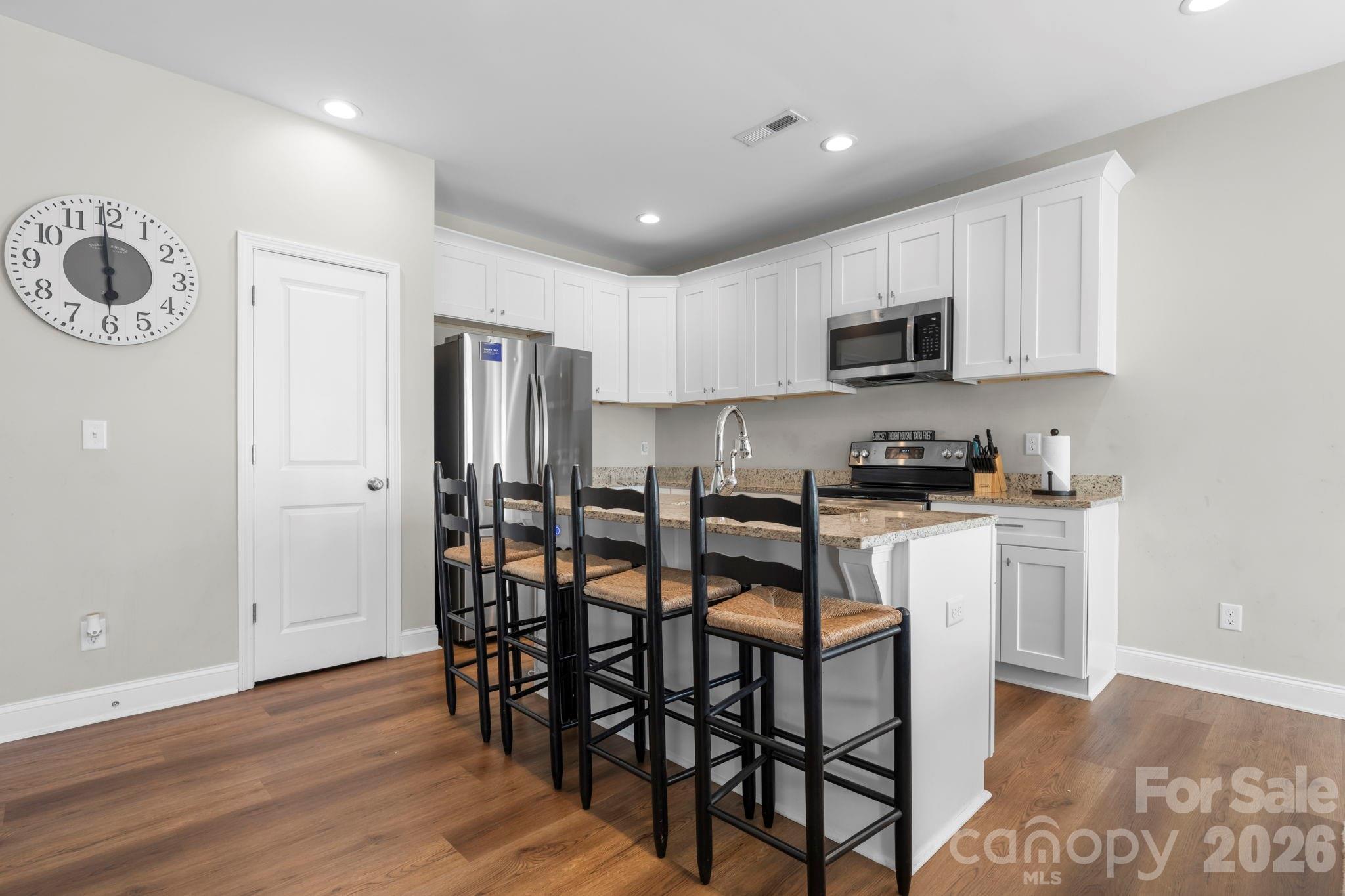 402 2nd Street Southwest Hickory, NC 28602 - Photo 5 of 24 a kitchen with stainless steel appliances kitchen island granite countertop a refrigerator a stove a microwave oven a sink with island and chairs with wooden floor