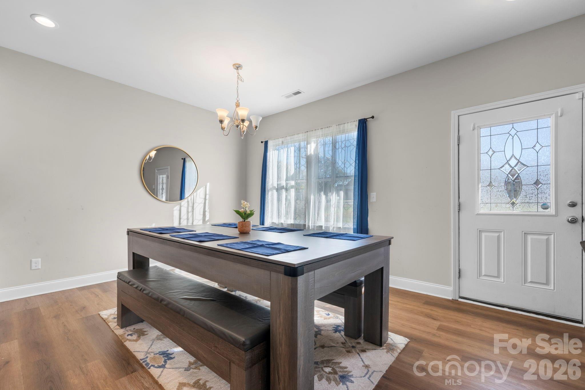 402 2nd Street Southwest Hickory, NC 28602 - Photo 8 of 24 a dining room with wooden floor a chandelier a wooden table and chairs