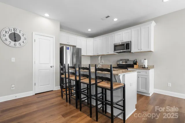 a kitchen with stainless steel appliances granite countertop a refrigerator stove a sink and a microwave with wooden floor