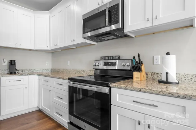 a kitchen with stainless steel appliances granite countertop white cabinets stove a sink and dishwasher