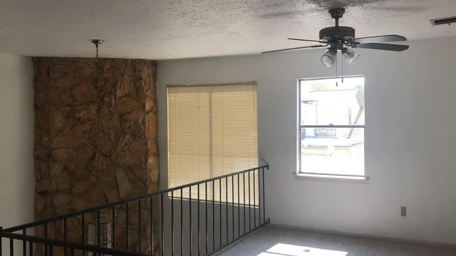 a view of a room with a window and a chandelier fan