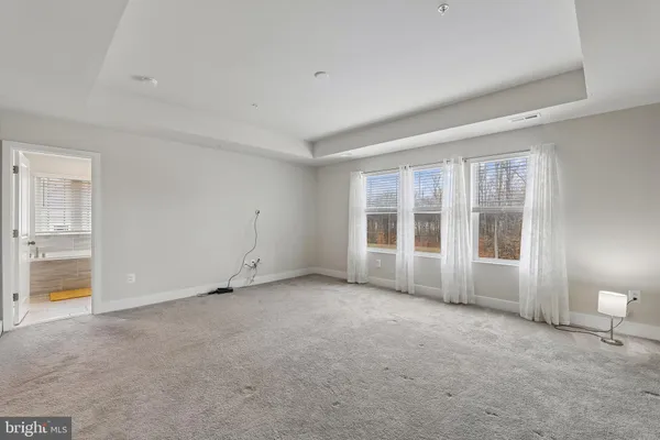 an empty room with chandelier fan and windows