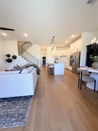 a living room with couches and kitchen view with wooden floor