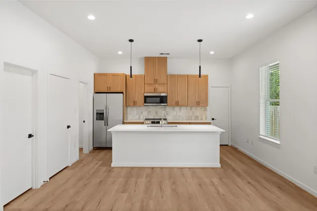 a kitchen with a stove a sink a kitchen island with wooden floor