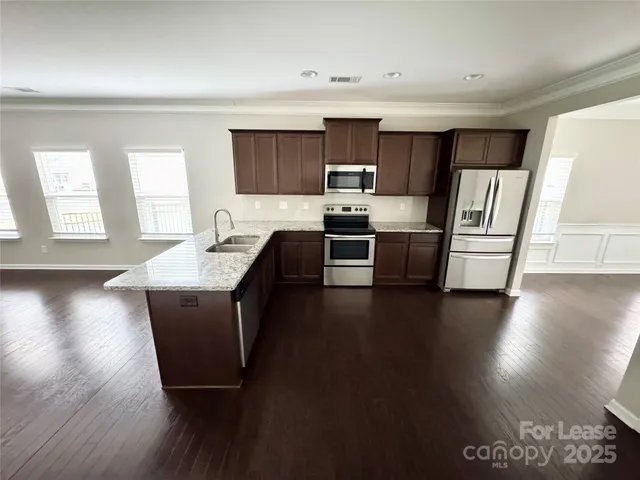 a kitchen with stainless steel appliances wooden floors and view living room