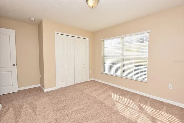 a view of an empty room with a window and a kitchen