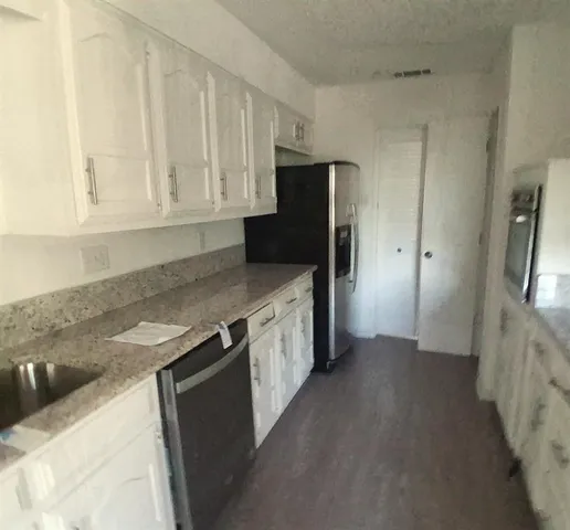 a kitchen with stainless steel appliances granite countertop white cabinets and refrigerator