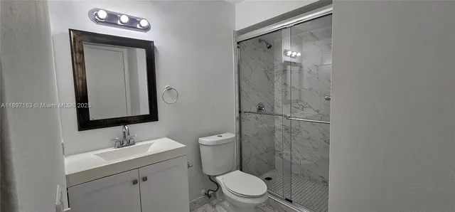 a bathroom with a toilet a sink a shower and mirror