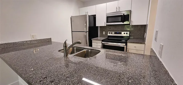 a kitchen with stainless steel appliances granite countertop a refrigerator and a sink
