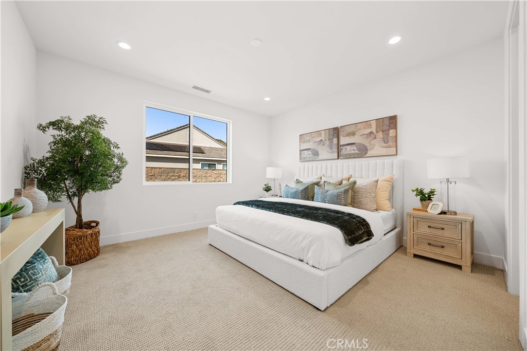 18302 Saddle Crest Silverado, CA 92676 - Photo 33 of 40 a spacious bedroom with a bed a couch and a potted plant