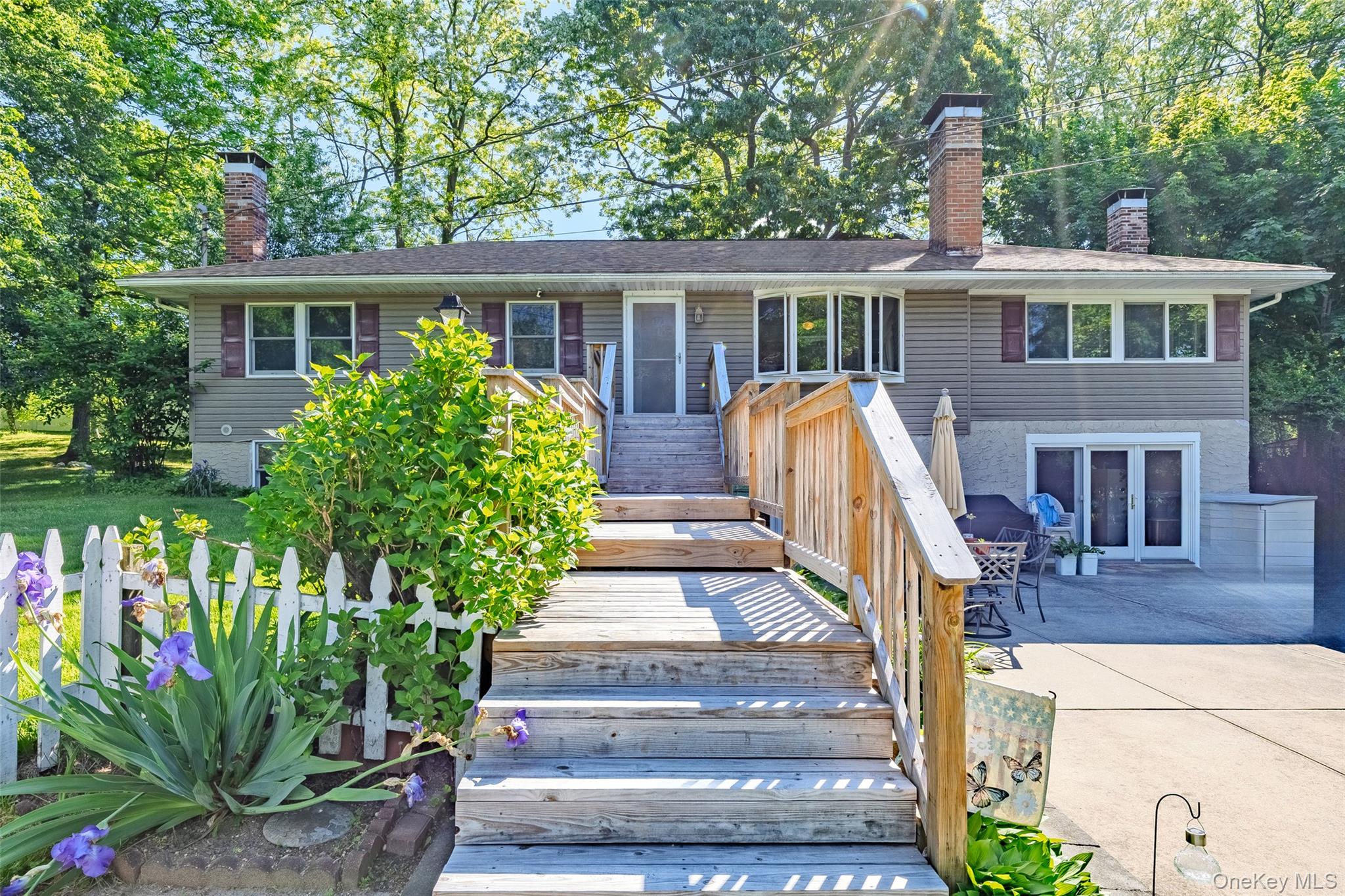 View of front of property featuring a chimney, french doors, a patio, and stairway