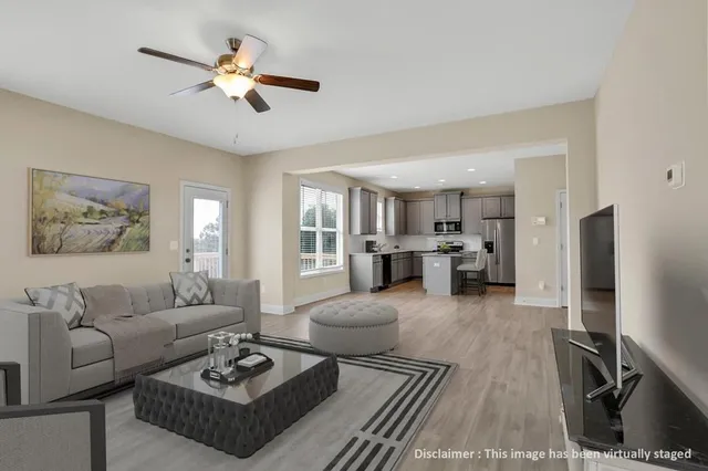a living room with furniture kitchen view and a window