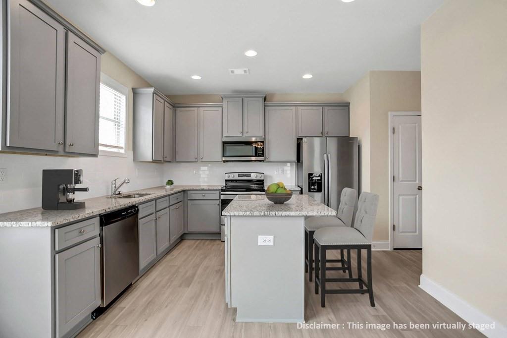 1852 Auburn Road, Unit GRANTVIEW Dacula, GA 30019 - Photo 8 of 31 a kitchen with kitchen island granite countertop wooden floors white cabinets and stainless steel appliances