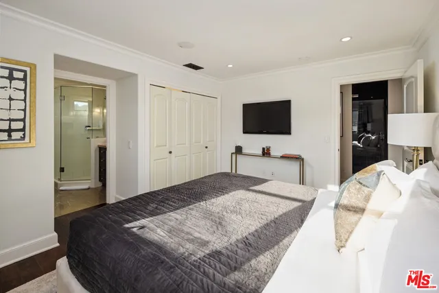 a bedroom with a bed and a flat tv screen on wall