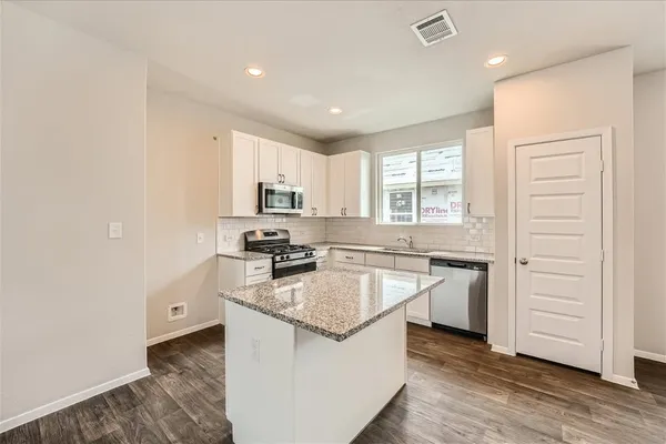 a kitchen with granite countertop white cabinets and white appliances
