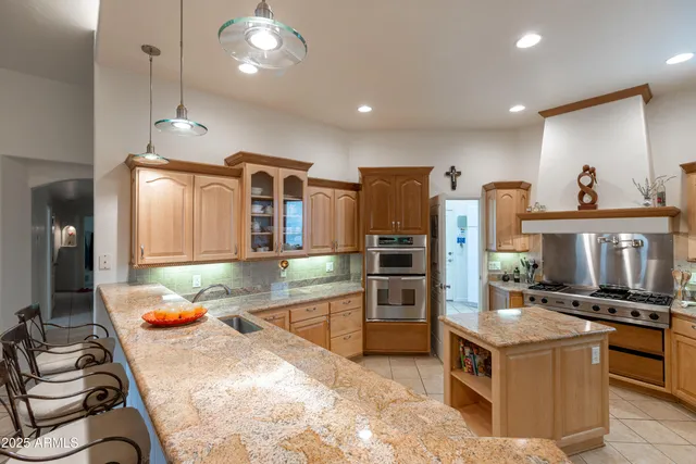 a kitchen with stainless steel appliances granite countertop a stove top oven a sink dishwasher and a refrigerator with wooden floor