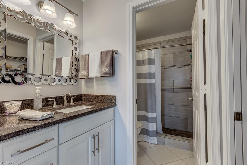 760 Augusta Boulevard, Unit D204 Naples, FL 34113 - Photo 11 of 20 a bathroom with a granite countertop sink a mirror and shower