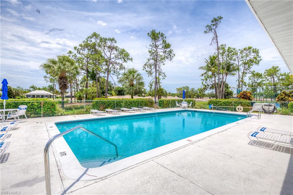 760 Augusta Boulevard, Unit D204 Naples, FL 34113 - Photo 19 of 20 a view of a swimming pool with a lawn chairs under an umbrella