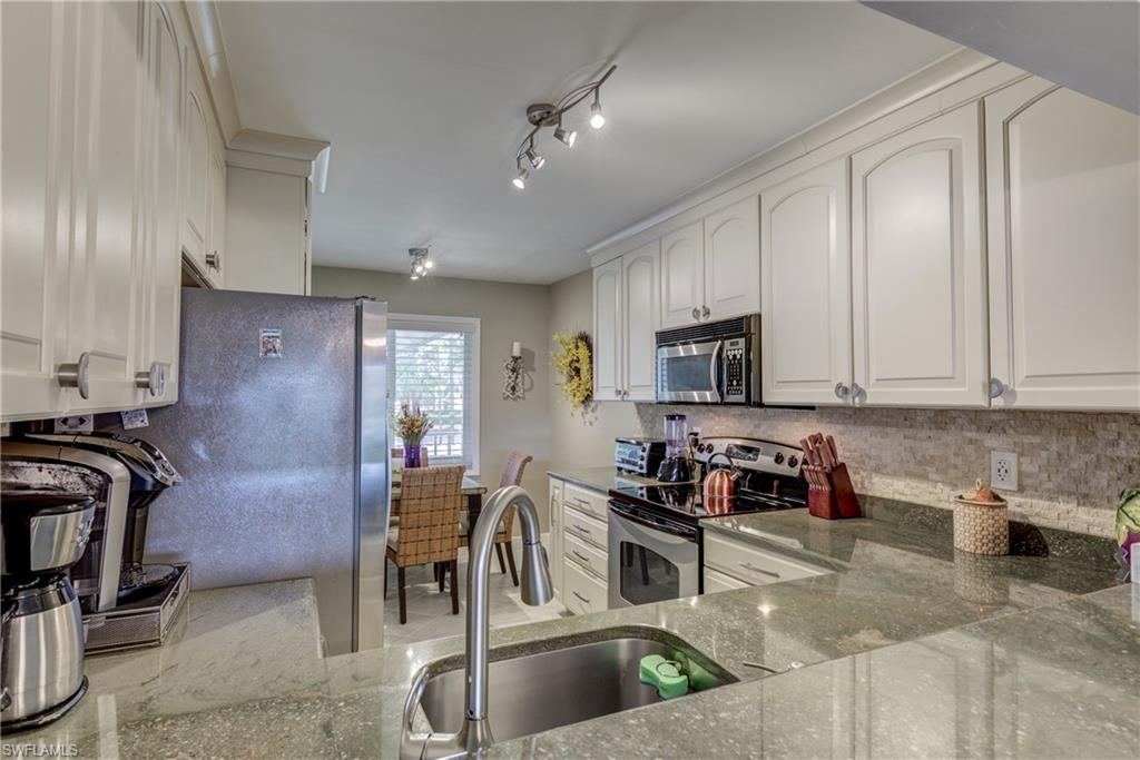 760 Augusta Boulevard, Unit D204 Naples, FL 34113 - Photo 5 of 20 a kitchen with stainless steel appliances granite countertop a sink a stove and a refrigerator