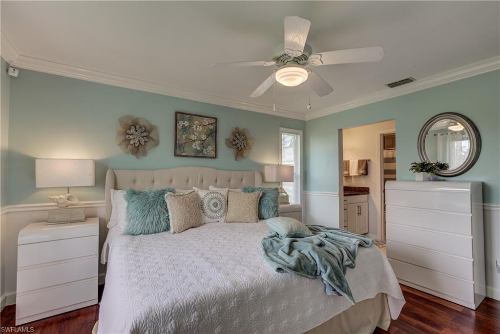 760 Augusta Boulevard, Unit D204 Naples, FL 34113 - Photo 10 of 20 a bedroom with a bed a mirror on dresser and a chandelier