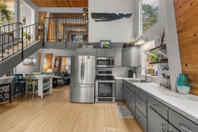 a kitchen with stainless steel appliances granite countertop a refrigerator a stove a sink dishwasher and a dining table with wooden floor