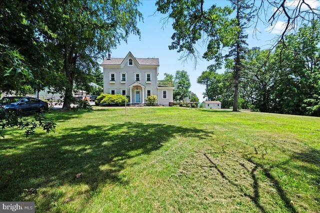 a view of a house with a big yard and large trees