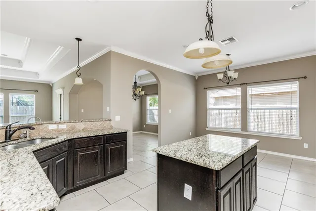 a kitchen with granite countertop cabinets a sink a stove and refrigerator