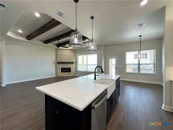 a open kitchen with a sink a chandelier stainless steel appliances and wooden floor
