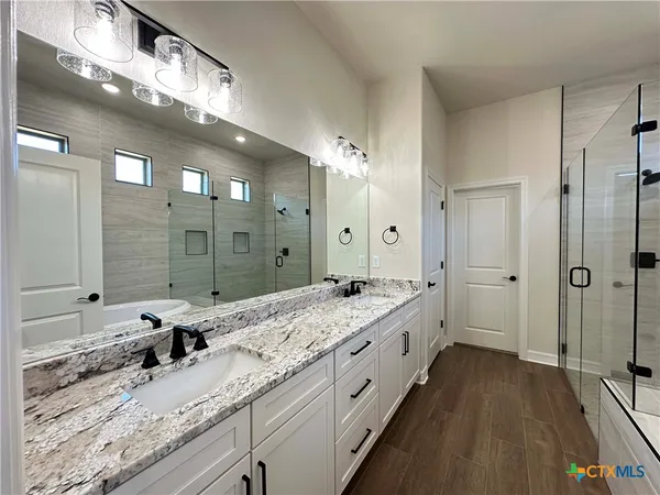 a bathroom with a granite countertop double vanity sink and a mirror