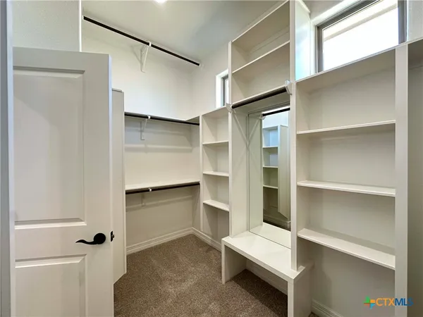 a room with a closet and wooden shelves
