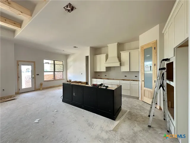 a living room with stainless steel appliances kitchen island granite countertop a refrigerator and a sink