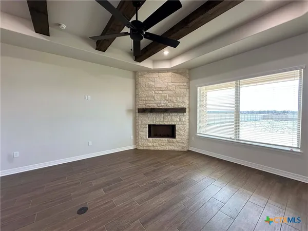 a view of an empty room with wooden floor fireplace and a window