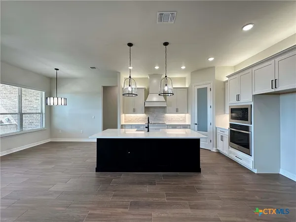 a view of kitchen with stainless steel appliances kitchen island granite countertop a stove a sink and a refrigerator