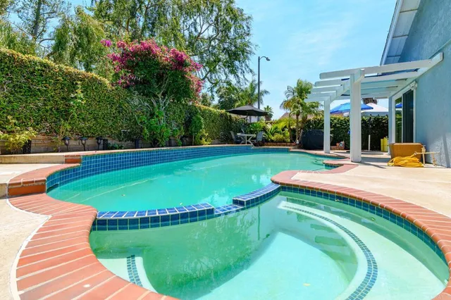 a backyard of a house with table and chairs under an umbrella
