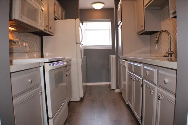 a kitchen with stainless steel appliances granite countertop white cabinets and a counter top space