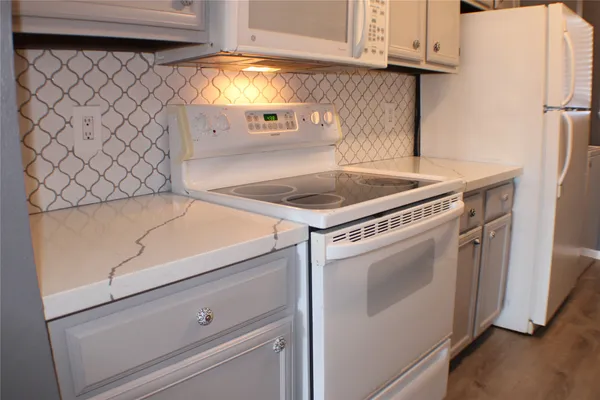 a kitchen with stainless steel appliances granite countertop a sink a stove and a refrigerator with wooden floor