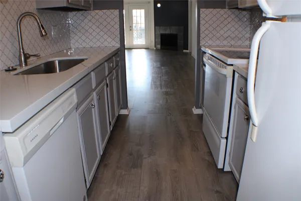 an empty room with windows fireplace and wooden floor