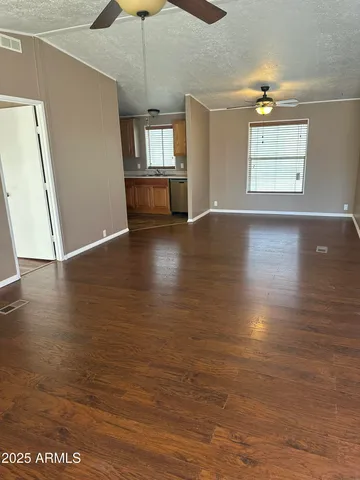 an empty room with wooden floor fan and windows