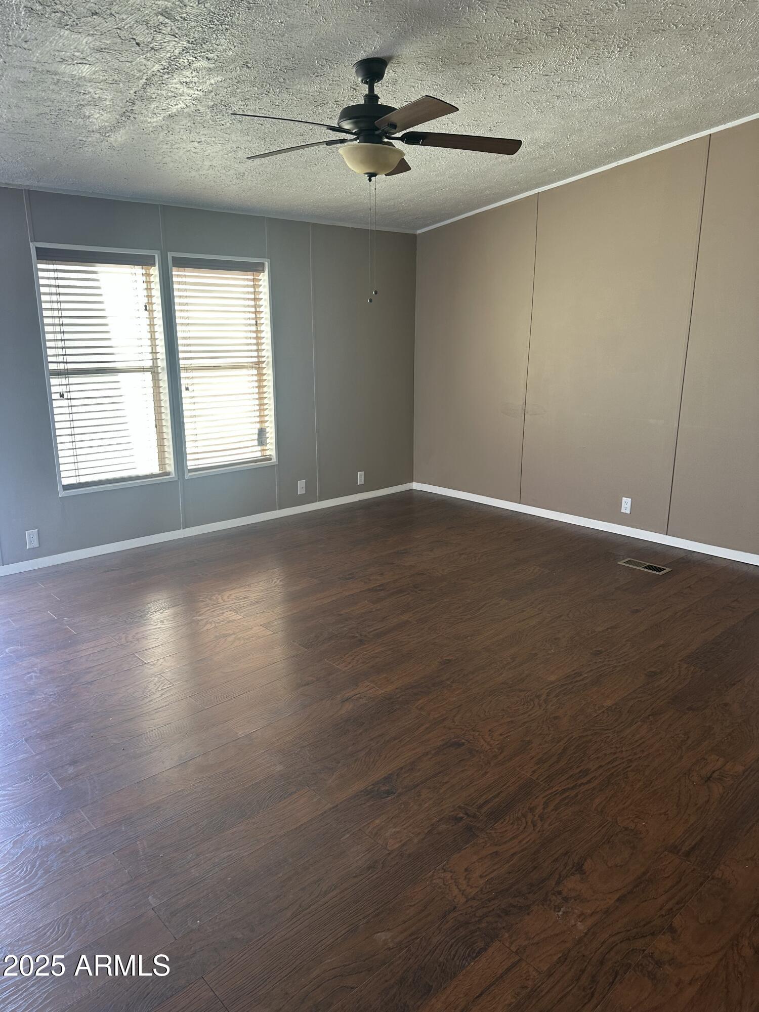 840 North Falton Road Maricopa, AZ 85139 - Photo 4 of 28 an empty room with wooden floor chandelier fan and windows