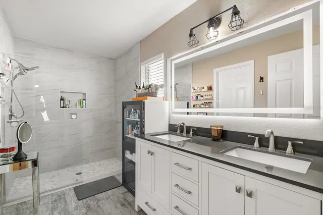 a bathroom with a granite countertop sink a mirror and shower