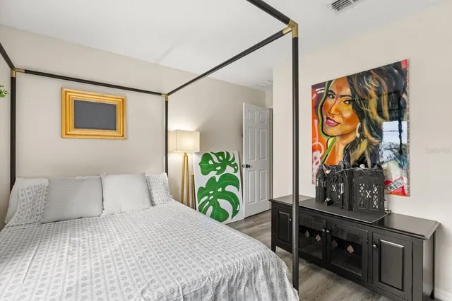 a bedroom with a bed and a potted plant on the dresser