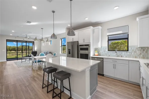 a kitchen with stainless steel appliances kitchen island granite countertop a table chairs stove and white cabinets