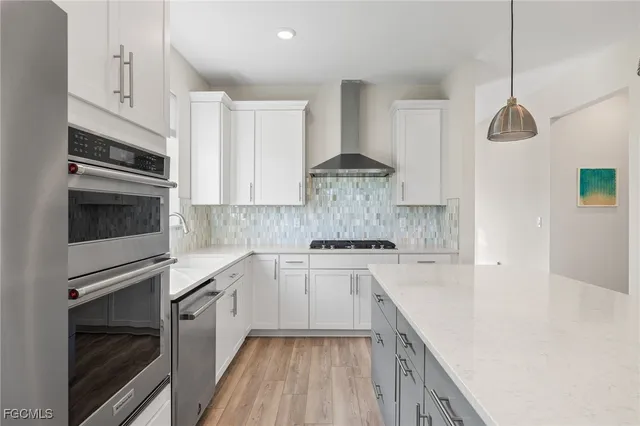a kitchen with granite countertop stainless steel appliances and white cabinets with wooden floor